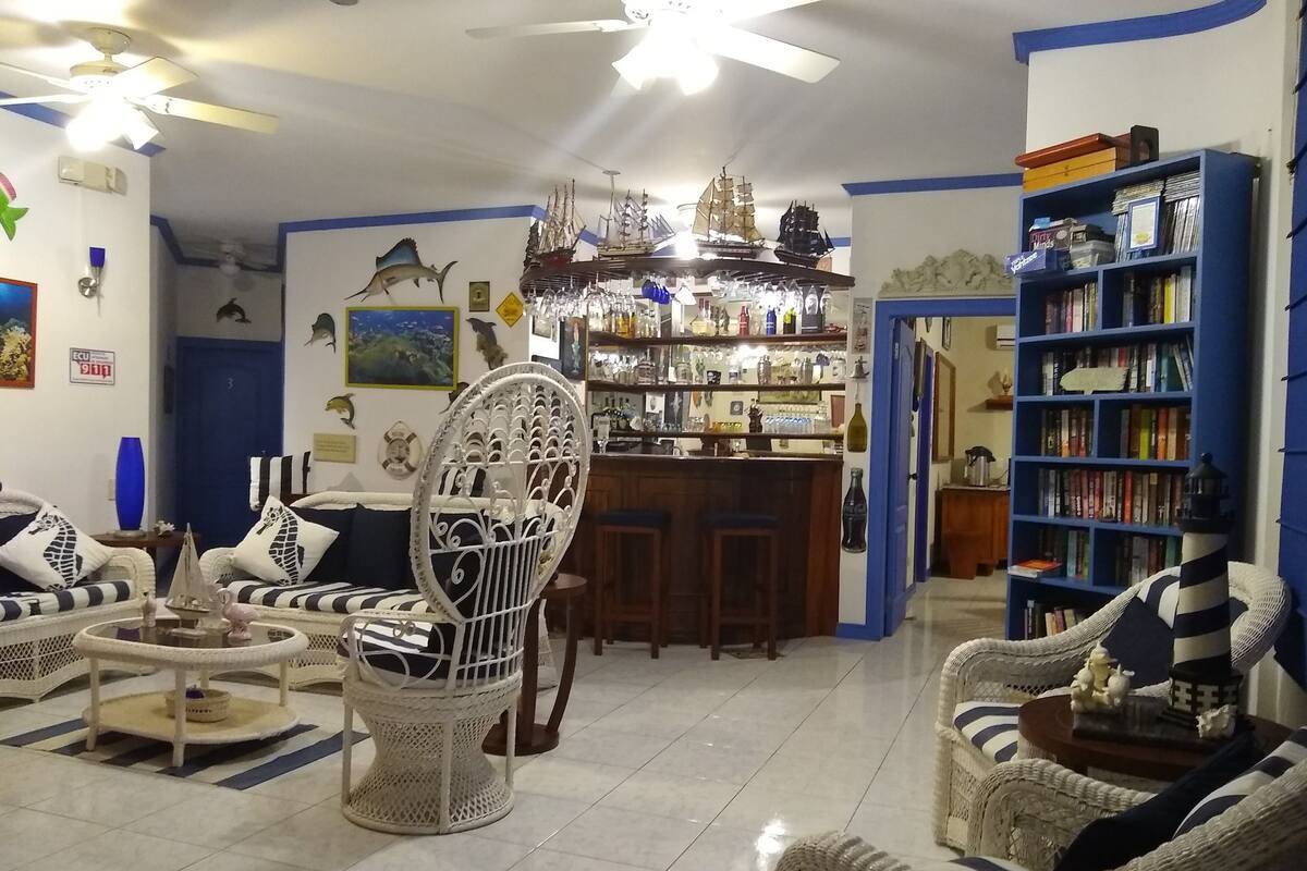 A living room with wicker furniture, a bar area, and a bookshelf.