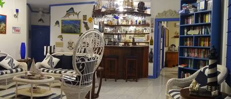 Una sala de estar con muebles de mimbre, una zona de bar y una estantería.
