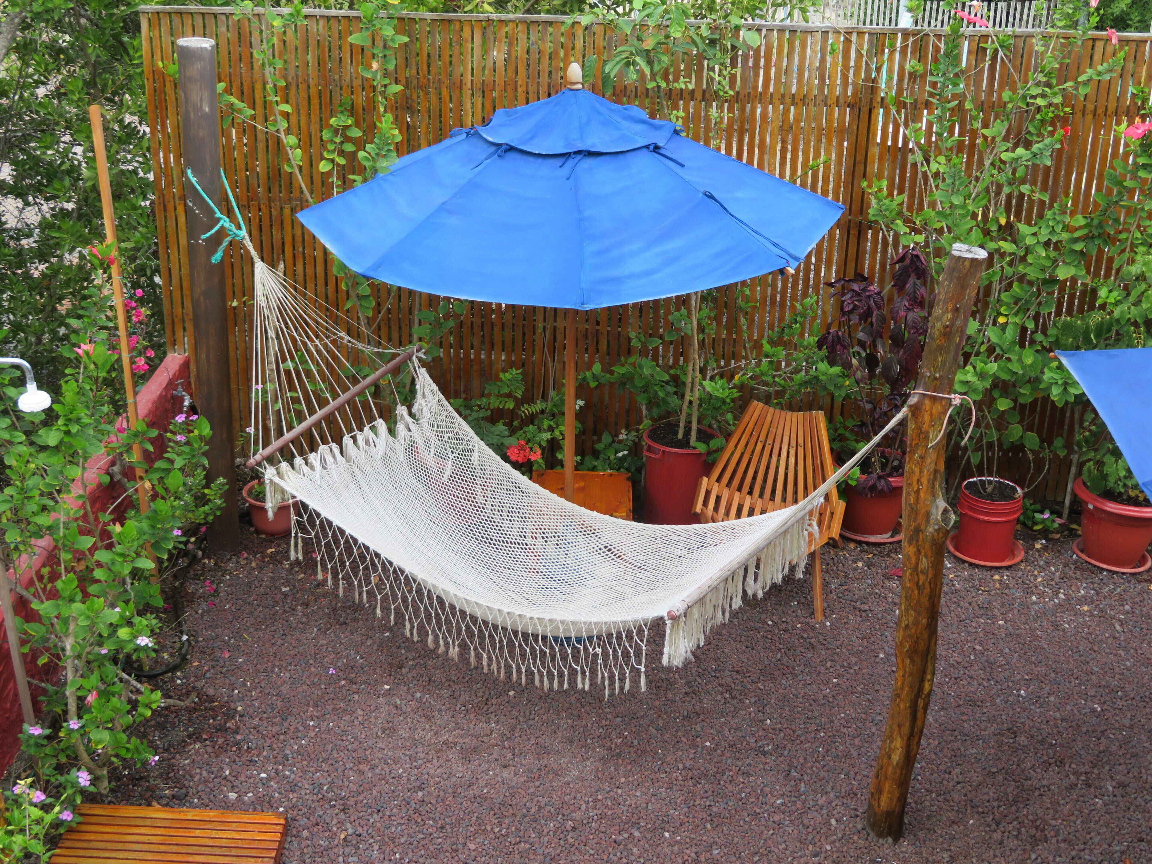 A hammock suspended between two wooden posts, with a blue umbrella above it.