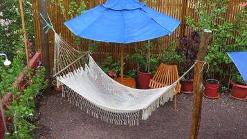 A hammock suspended between two wooden posts, with a blue umbrella above it.