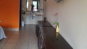 Habitación de hotel con un aparador de madera, un televisor en la pared y un baño visible a través de una puerta abierta.