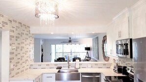 A modern kitchen with a central island, stainless steel appliances, and a chandelier.