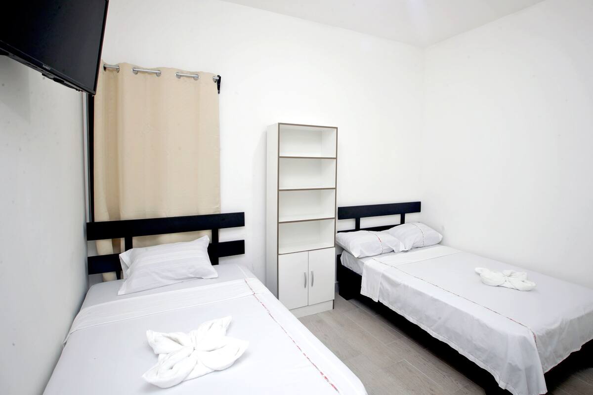 A room with two single beds, a wardrobe, and a television.