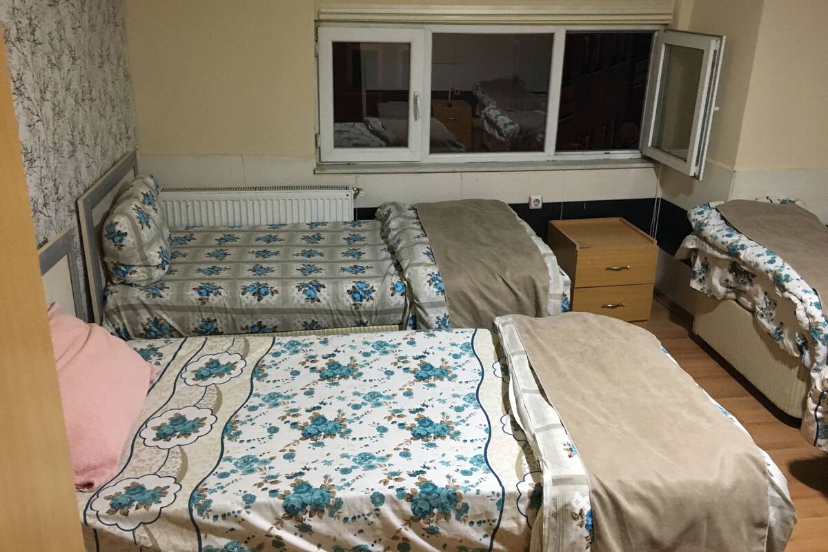 Ein kleiner, kompakter Raum mit zwei Betten, einem Heizkörper, einem Fenster und Holzboden.