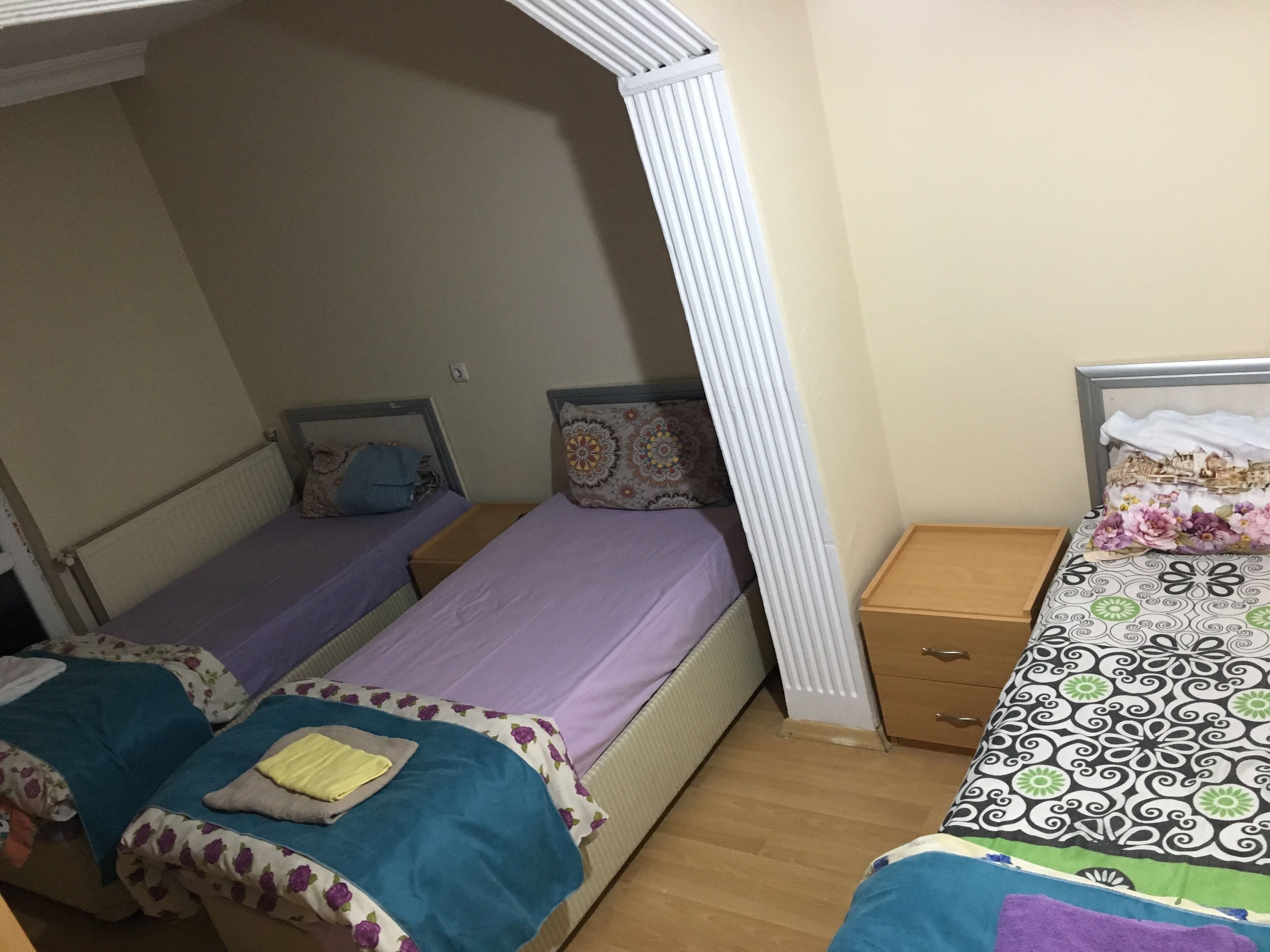 Una habitación con dos camas individuales, una mesita de noche de madera y un radiador blanco.