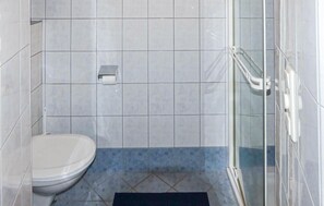 Ein Badezimmer mit Toilette, einer Duschkabine aus Glas und blau gefliestem Boden.