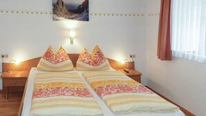 Een tweepersoonsbed met behang, twee bedlampjes, een nachtkastje en een wandlamp.