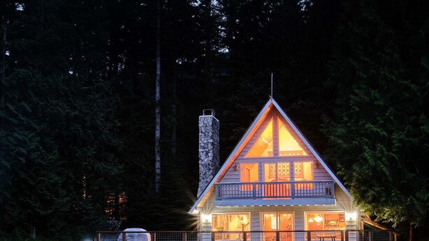 A cabin with a stone chimney, a balcony, and a deck area. - Diamond on the Sky: Riverfront mountain lodge w/ views, AC & WiFi (Skykomish)