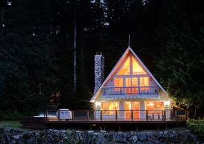 A cabin with a stone chimney, a balcony, and a deck area. - Diamond on the Sky: Riverfront mountain lodge w/ views, AC & WiFi (Skykomish)