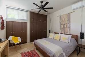 Un dormitorio con cama, escritorio, silla, ventilador de techo y ventana con persianas.