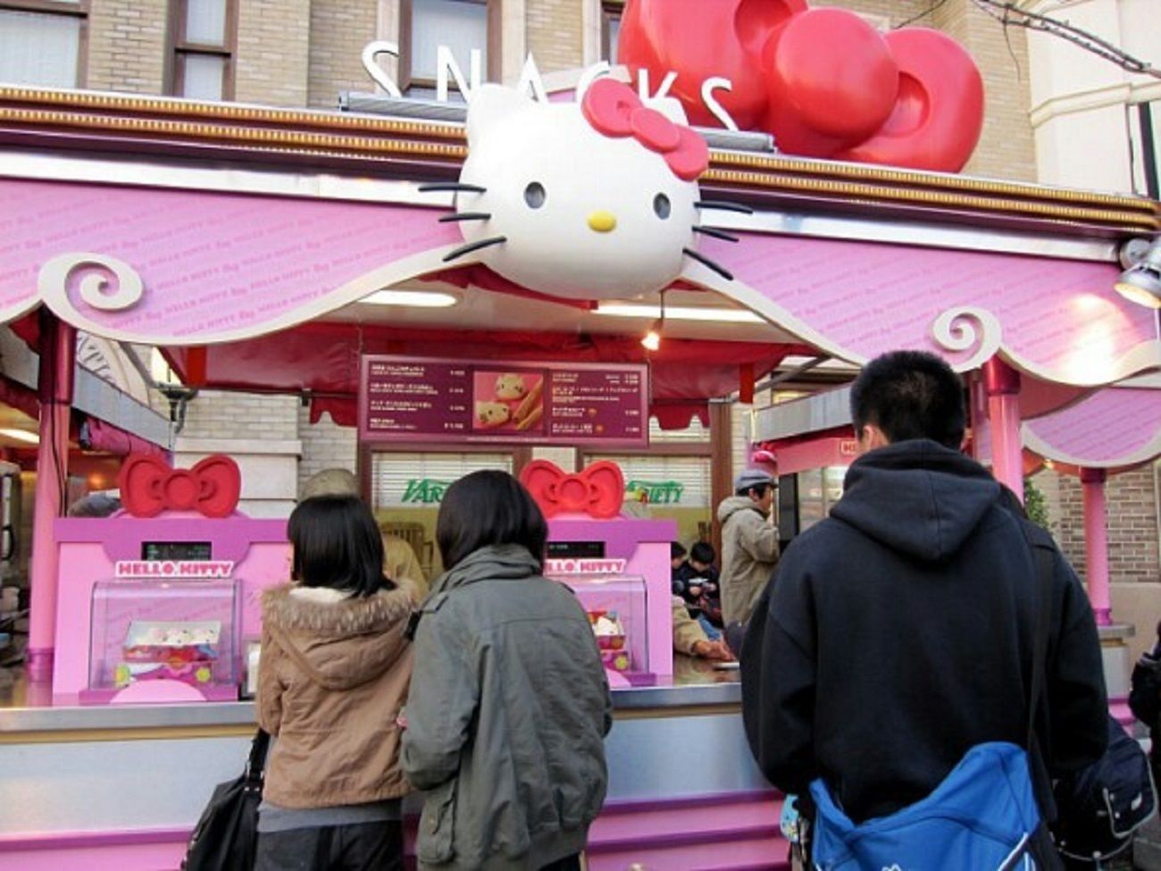 Un petit kiosque à snacks sur le thème de Hello Kitty, avec une enseigne Hello Kitty et un auvent rose.