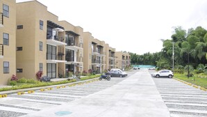 Une rue résidentielle bordée d’immeubles à plusieurs étages, avec des voitures garées et un ciel dégagé.
