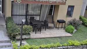 Un espace patio aménagé avec une table et des chaises, une petite table et une plante en pot.