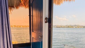 Une chambre avec une grande fenêtre donnant sur un plan d’eau et une terrasse.