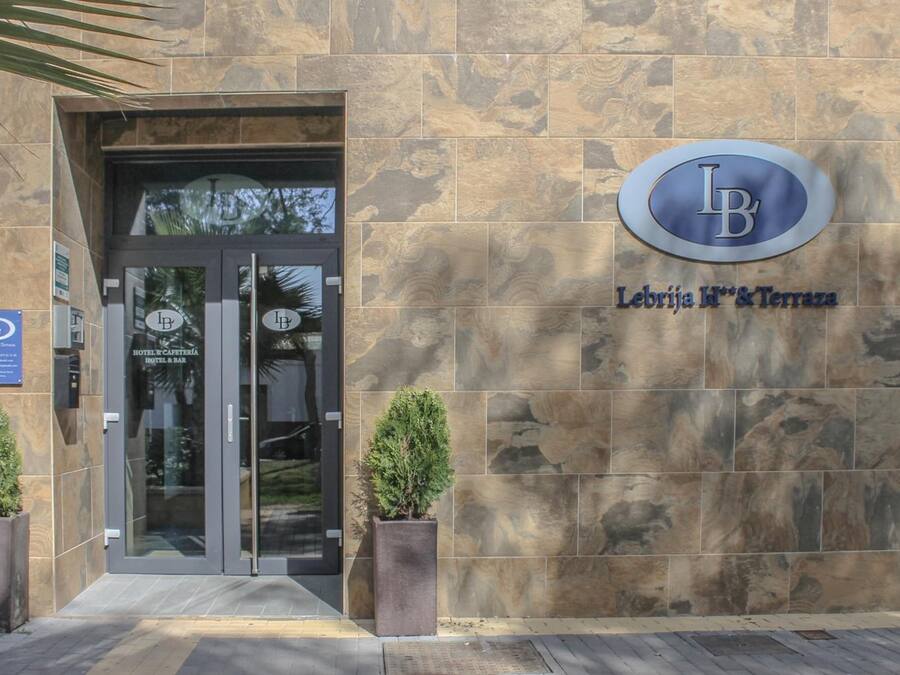 The entrance to Lebrija Hotel & Spa with a stone facade and a glass door.