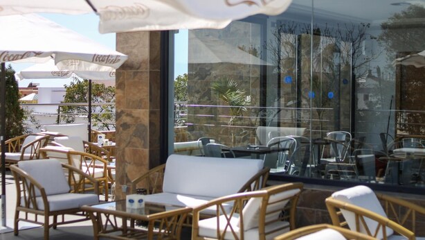 An outdoor seating area with wicker furniture and white cushions, featuring Coca-Cola branded umbrellas. - Hotel LB Lebrija by MA 22 Puntos (Lebrija)