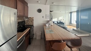 Moderni keittiö, jossa on ruostumattomasta teräksestä valmistetut kodinkoneet, puinen työtaso ja näkymä olohuoneeseen.