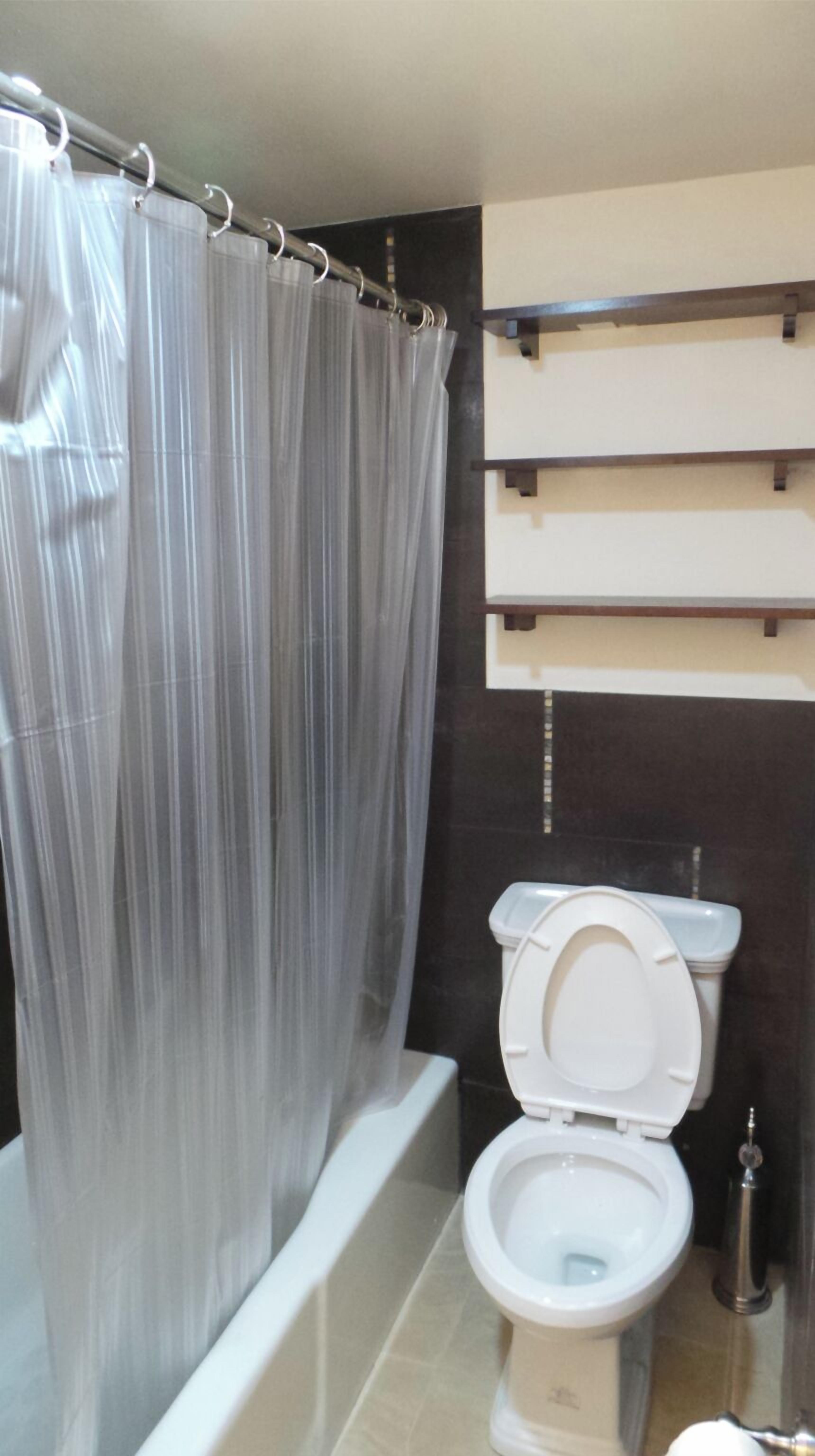 Een badkamer met douchegordijn, toilet en een plankunit.