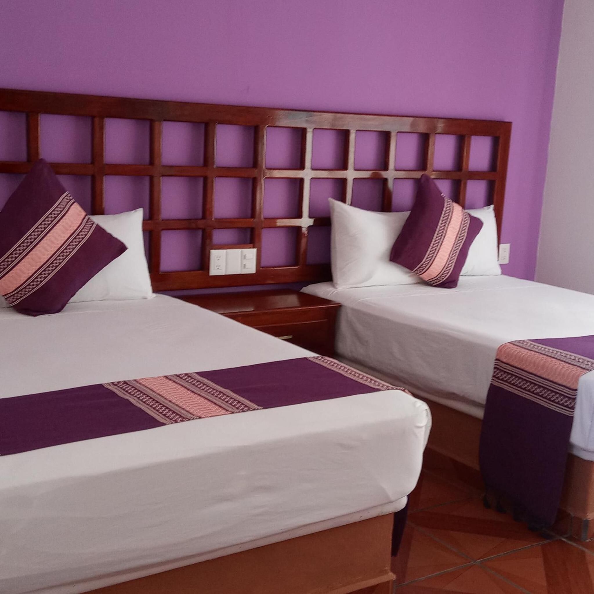A hotel room with two beds, each with a wooden headboard and white bedding.