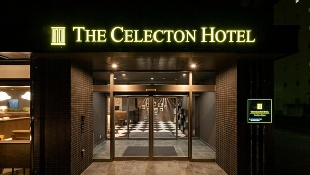 Der Eingangsbereich des Cellecton Hotels mit Schachbrettmuster-Boden, Glasüren und einer Ziegel-Fassade.