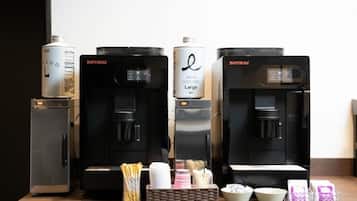 Cuatro cafeteras con cápsulas de café y un refrigerador pequeño.