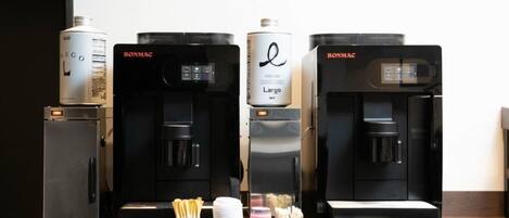 Vier Kaffeemaschinen mit Kaffeekapseln und ein kleiner Kühlschrank.