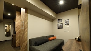 Ein modernes Zimmer mit einem grauen Sofa, einer Holzvertäfelung und gerahmten Bildern an der Wand.