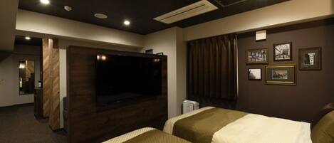A hotel room with two beds, a large flat-screen TV, a wooden accent wall, and framed pictures on the wall.