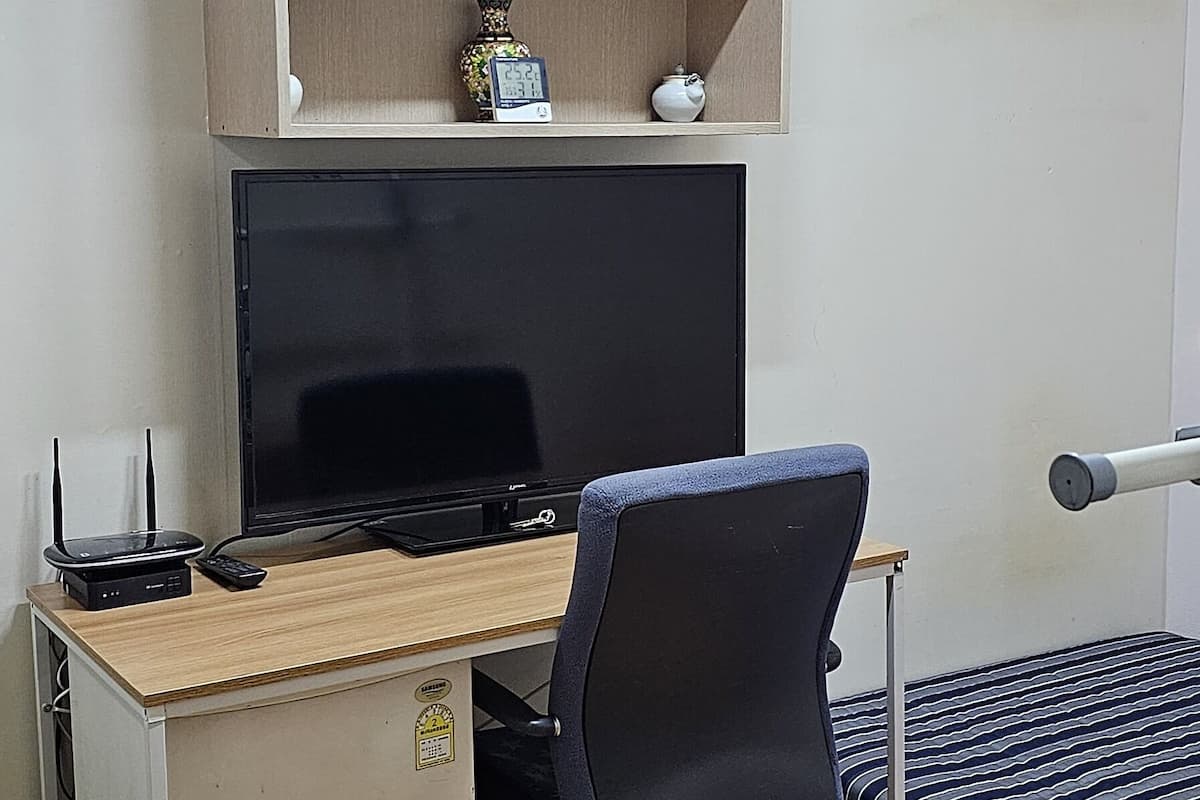 Une petite pièce comprenant un bureau, une chaise et un lit.