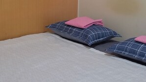 A bed with a grey bedspread and two pillows with a blue and pink pattern. - Jukjeon Guesthouse iwantlivingtel (Yongin)