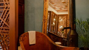 A vintage bathtub with a towel, a large mirror, and a wood partition in a room with a checkered ceiling. - Hotel Boutique Casa Zevallos (Córdoba)