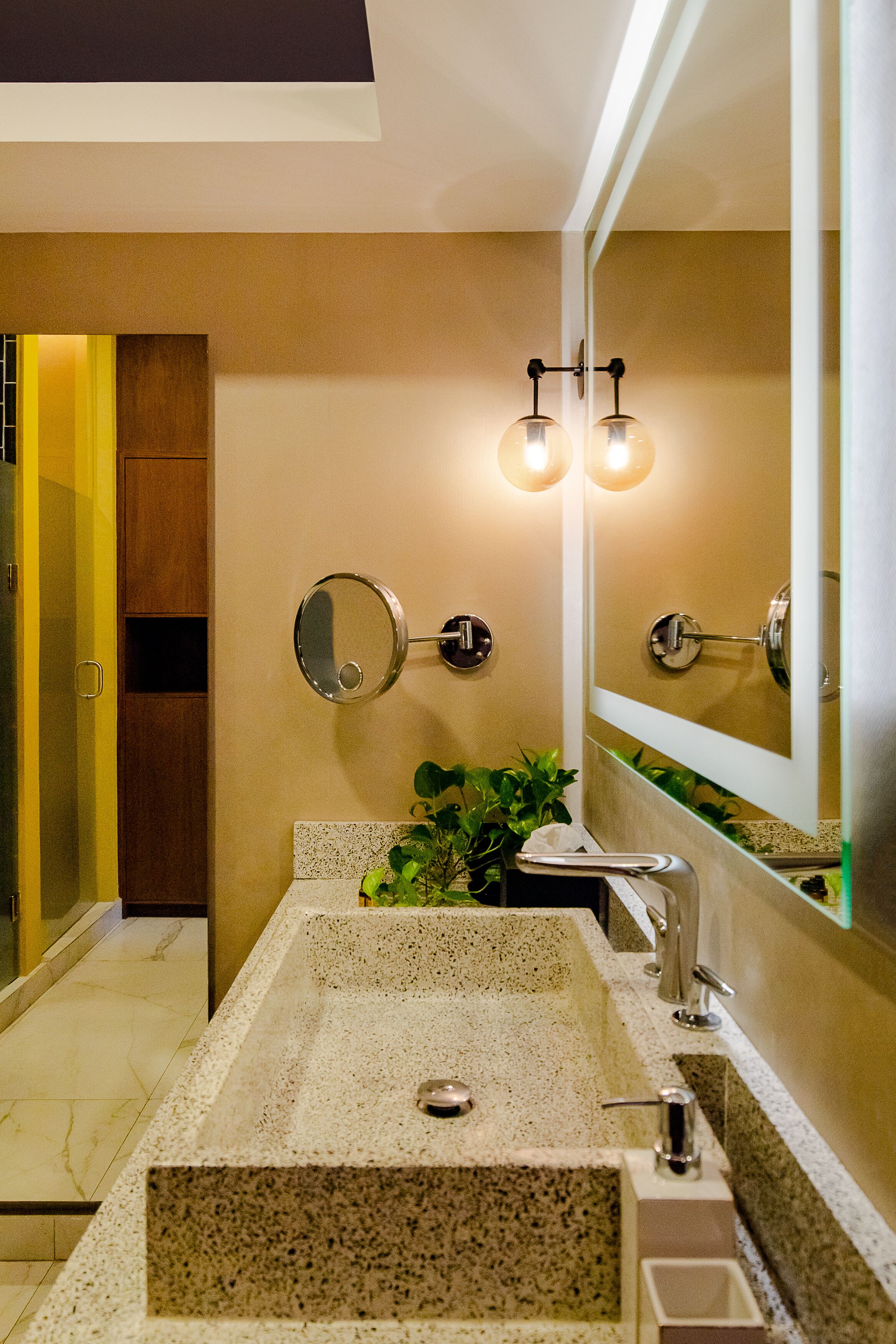 A bathroom with a granite sink, a mirror, and two wall-mounted lights.