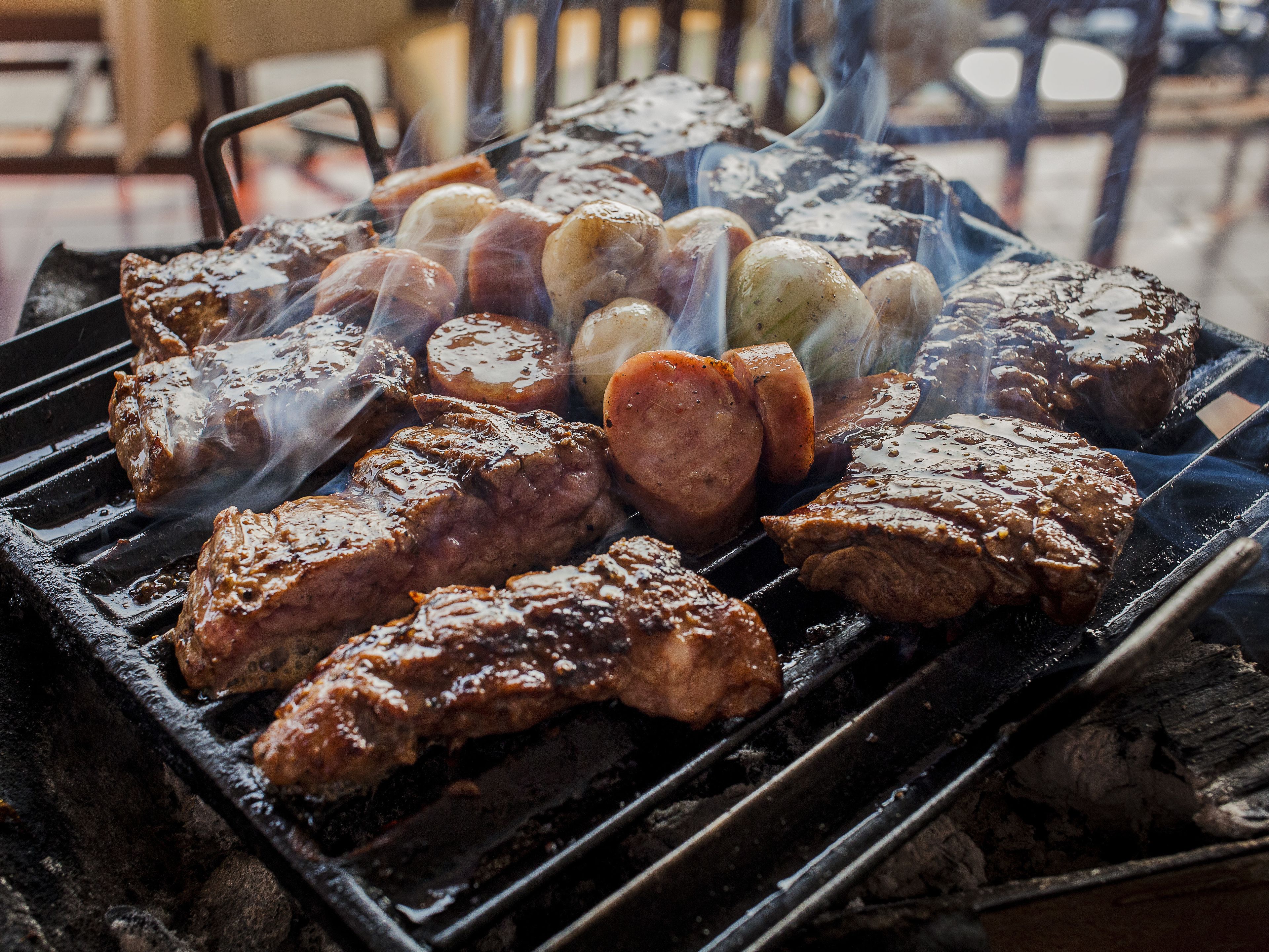 Una parrilla con diferentes carnes y salchichas asándose.