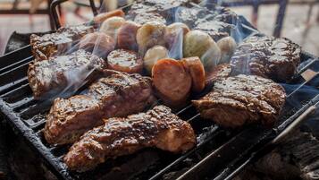 Una parrilla con diferentes carnes y salchichas asándose.