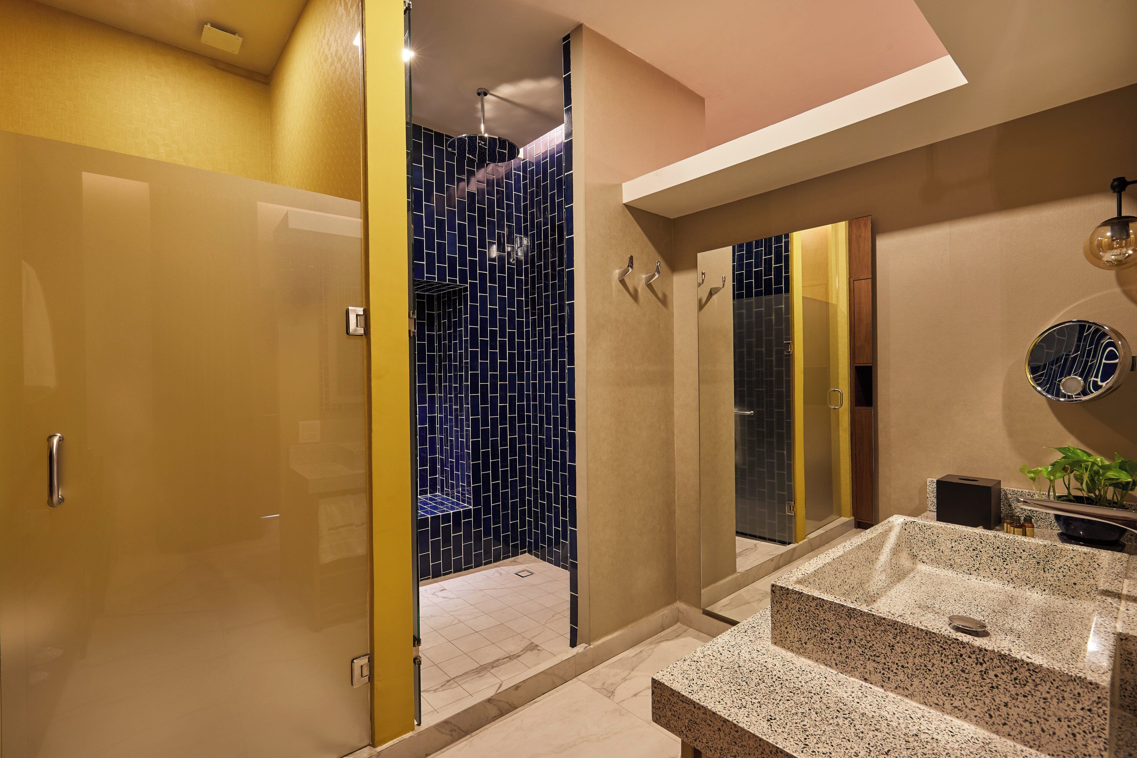 A modern bathroom with a glass shower enclosure, a granite sink, and a large mirror.