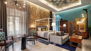 A bedroom with a stone wall, a canopy bed, a round table, and a vintage lamp. - Hotel Boutique Casa Zevallos (Córdoba)