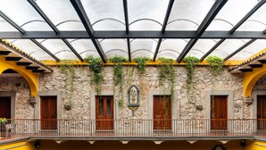 A building with a yellow facade, stone walls, and a balcony with a metal railing. - Hotel Boutique Casa Zevallos (Córdoba)