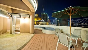 Terraza con asientos al aire libre y vista a un edificio con cúpula y grúas de construcción.