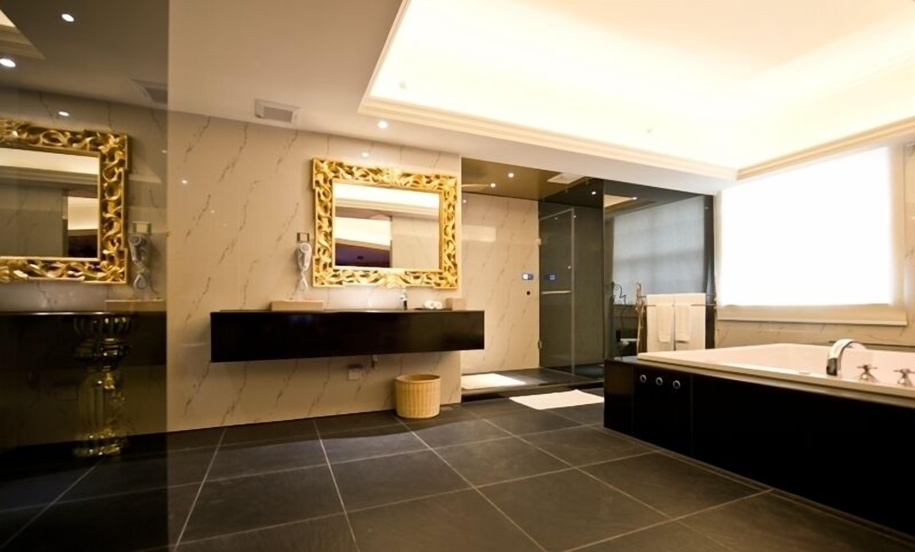 A modern bathroom with a large mirror, a vanity with a sink, and a separate bathtub area.