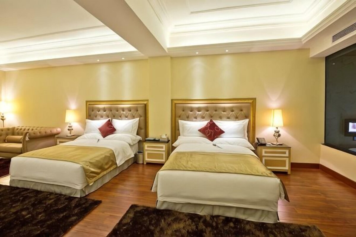 A hotel room with two beds, a sofa, and a large mirror.
