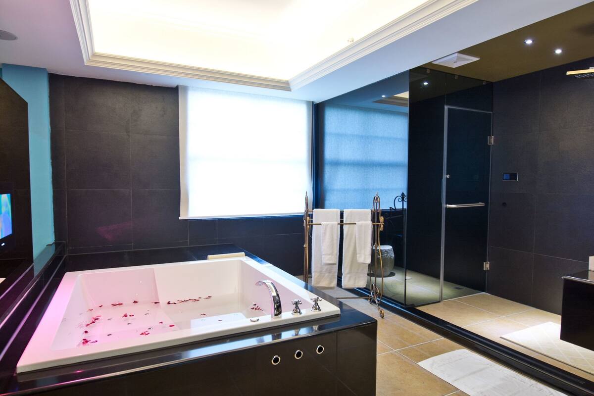 A modern bathroom with a large bathtub, a glass shower enclosure, and a vanity with a mirror.