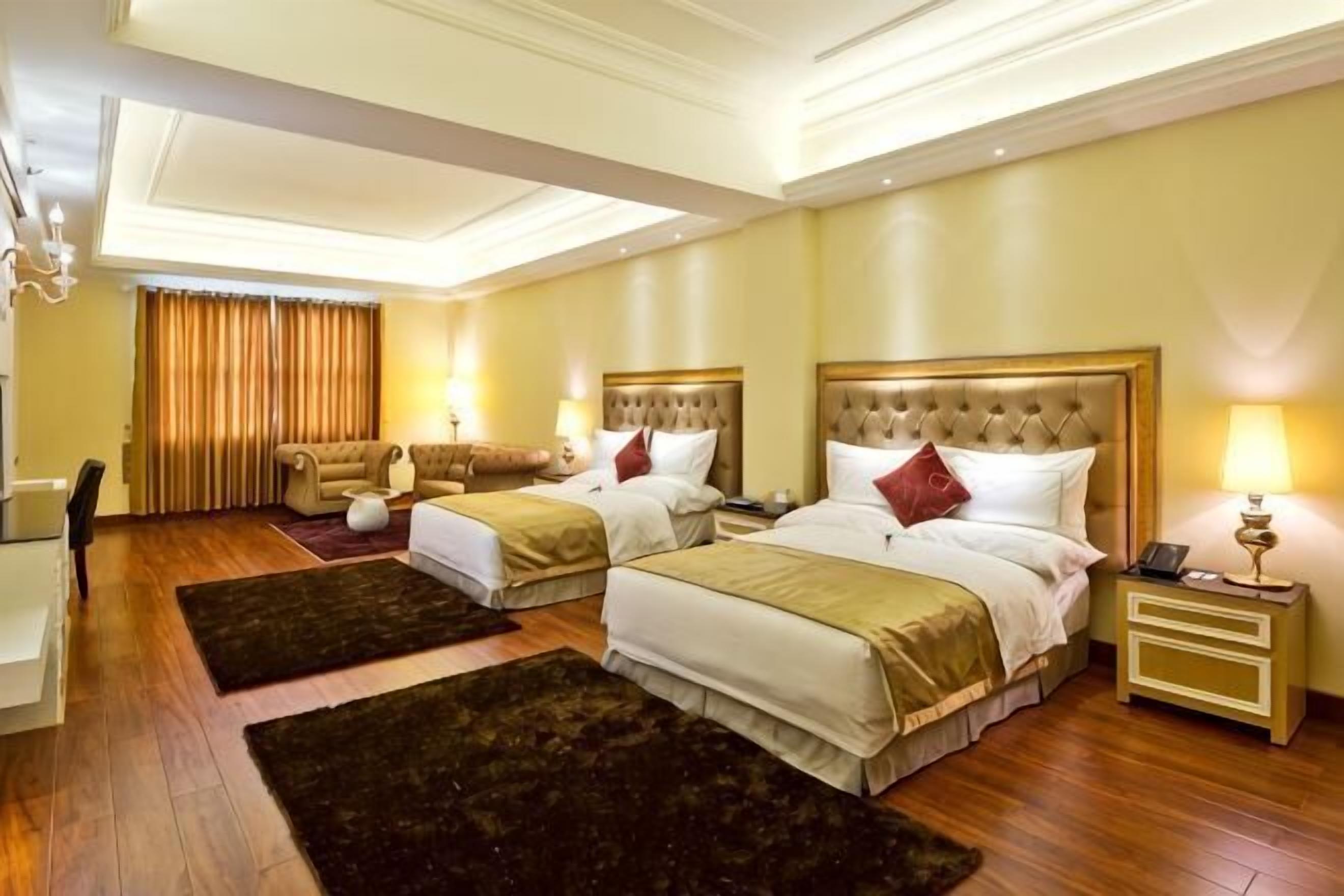 Une chambre d’hôtel avec deux lits, un bureau et une chaise.