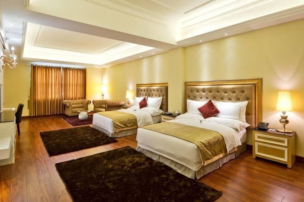 A hotel room with two beds, a desk, and a chair.