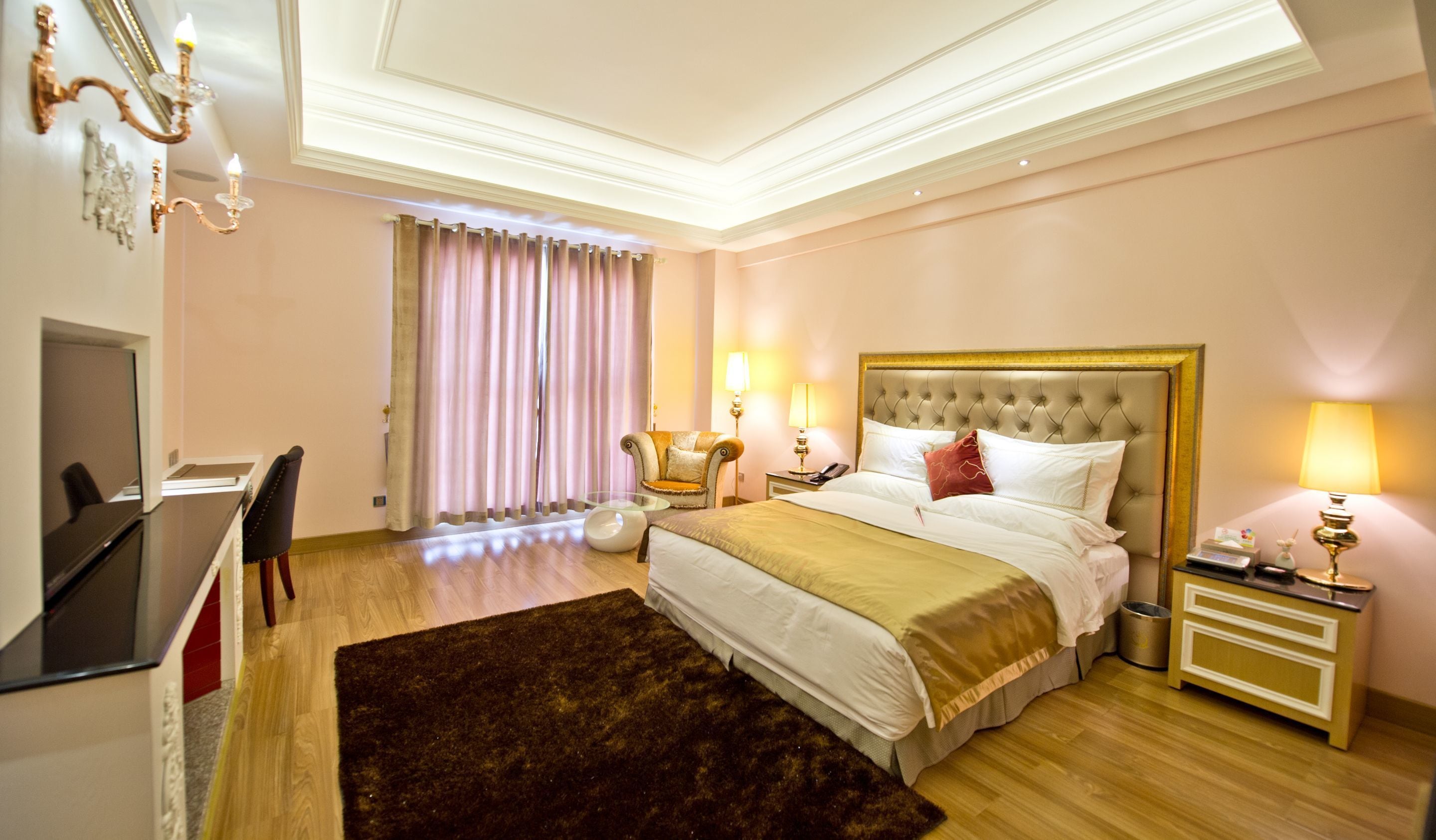 Une chambre d’hôtel avec un grand lit, un bureau, une chaise, une petite table et une poubelle.