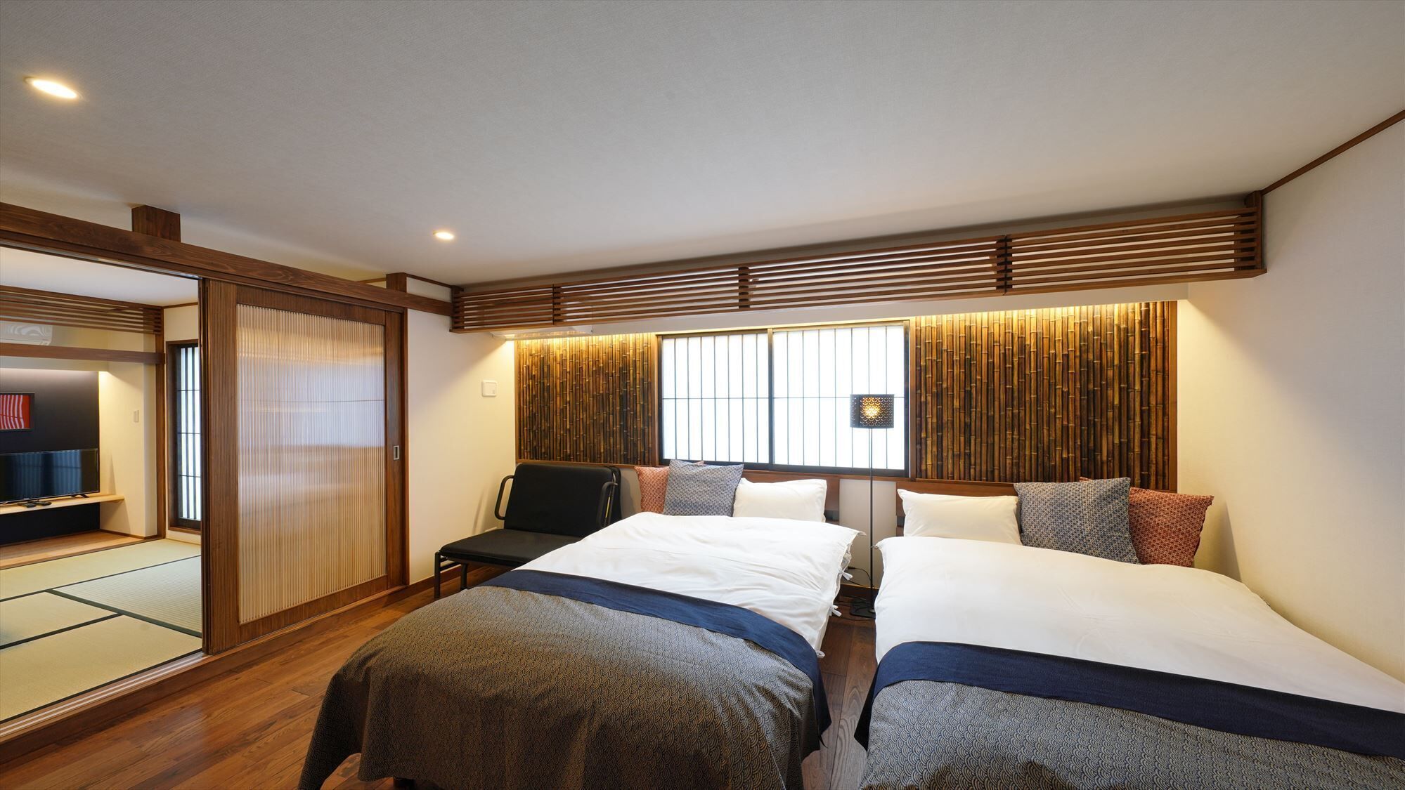 A hotel room with two beds, a seating area, and a television.