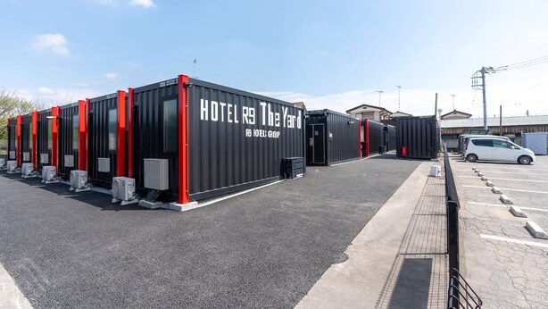 A row of black hotel containers with red accents, labeled "HOTEL R9 The Yard."