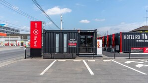 A hotel entrance with a red sign, a black and red facade, and a clear sky.