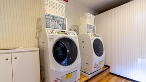 Two front-loading washing machines in a laundry room with wooden flooring and striped wallpaper.