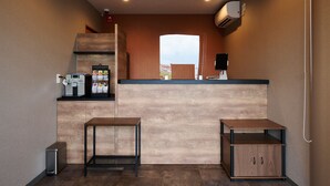 A compact kitchenette with a coffee machine, a small refrigerator, and a wooden counter.