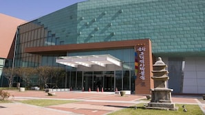 A modern building with a glass facade and a stone monument in front. - Golden Bee Motel (Gunsan)